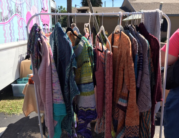 Rack of hand-knit shawls and sweaters