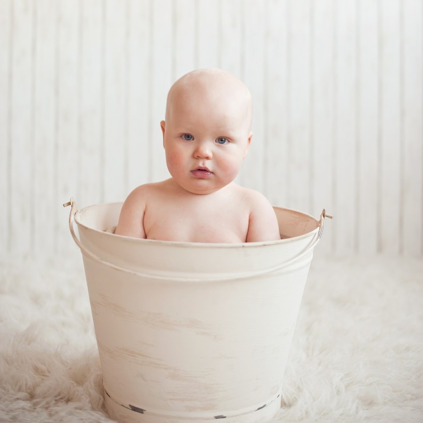 Bald baby in a white bucket