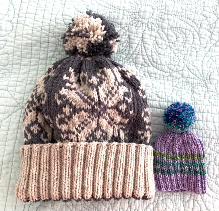 Two hand knit hats with pompoms