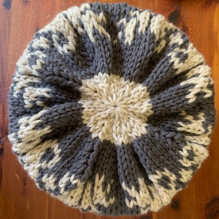 Top finished image of snowflake hat with bumps and white yarn used