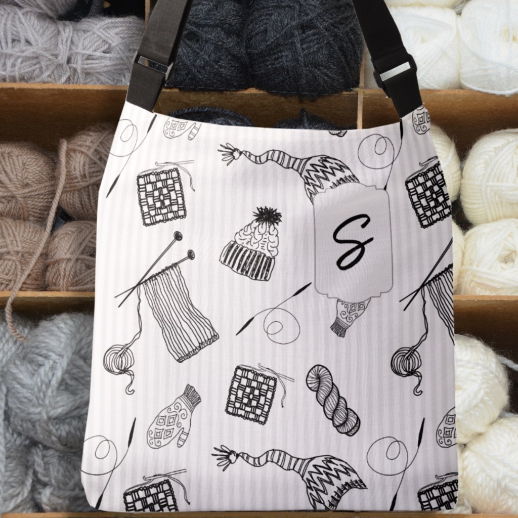 A tote bag featuring black and white illustrations of knitting items such as yarn balls, knitting needles, mittens, and hats, set against a light background.